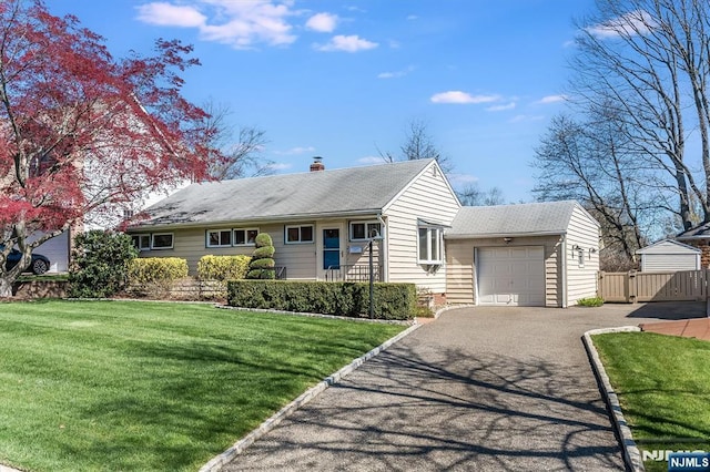 view of front of house featuring fence, a garage, a front yard, a chimney, and driveway