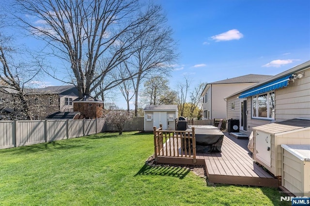 view of yard featuring a storage shed, an outdoor structure, a wooden deck, and a fenced backyard