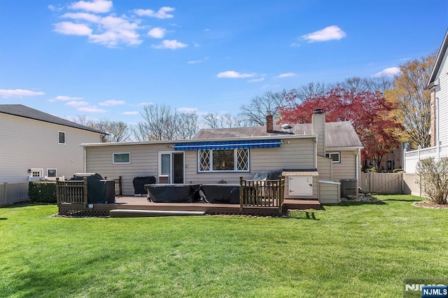 rear view of house with a wooden deck, a fenced backyard, a chimney, cooling unit, and a yard
