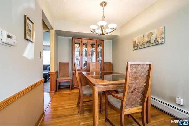 dining space featuring light wood-style floors, a notable chandelier, and baseboard heating