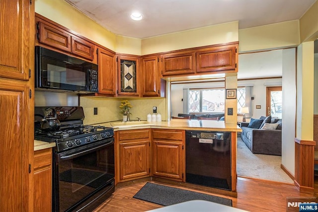 kitchen with light countertops, a healthy amount of sunlight, black appliances, and dark wood-type flooring