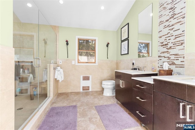bathroom with visible vents, double vanity, toilet, tile walls, and a stall shower