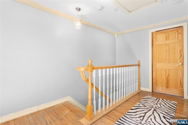 hallway with crown molding, baseboards, wood finished floors, and an upstairs landing