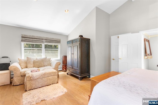 bedroom featuring light wood-type flooring, a baseboard radiator, and high vaulted ceiling