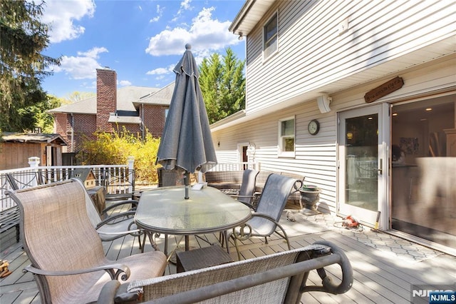wooden deck with a storage unit, an outbuilding, and outdoor dining space