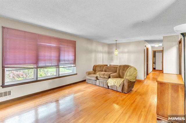 living room with baseboards, visible vents, and light wood finished floors
