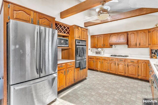 kitchen featuring light countertops, stainless steel appliances, brown cabinetry, and beam ceiling
