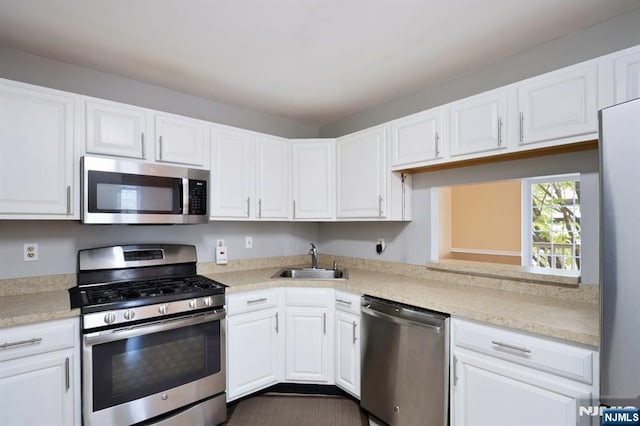 kitchen featuring a sink, appliances with stainless steel finishes, white cabinetry, and light countertops