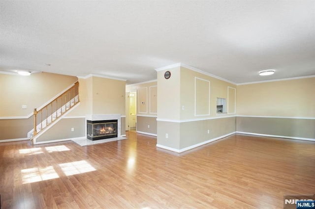 unfurnished living room featuring baseboards, ornamental molding, and light wood-style flooring