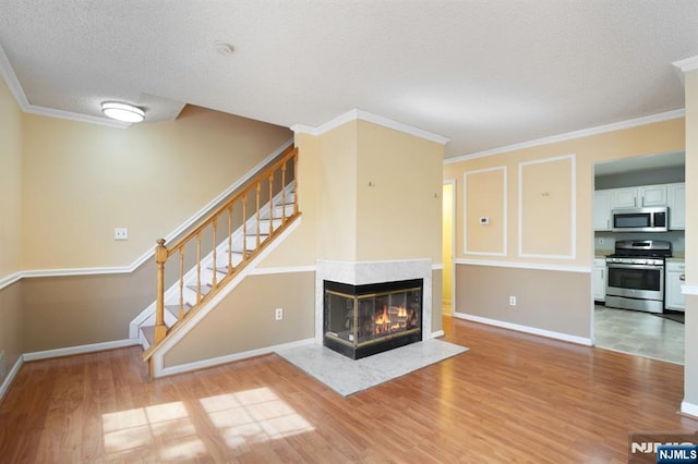 unfurnished living room featuring light wood-style floors, a textured ceiling, stairs, and crown molding