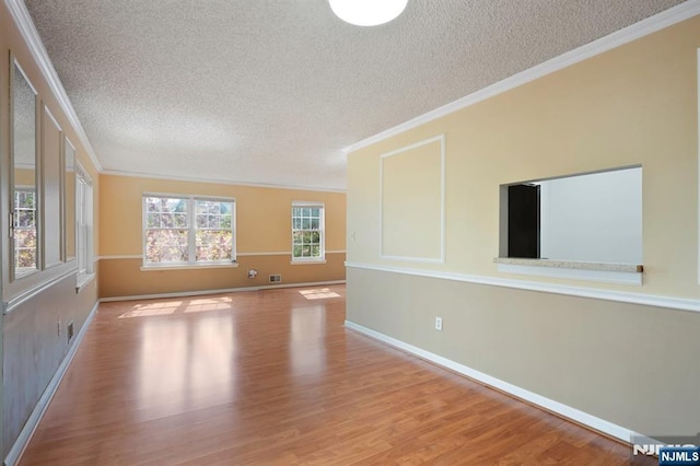 unfurnished living room featuring crown molding, baseboards, a textured ceiling, and wood finished floors