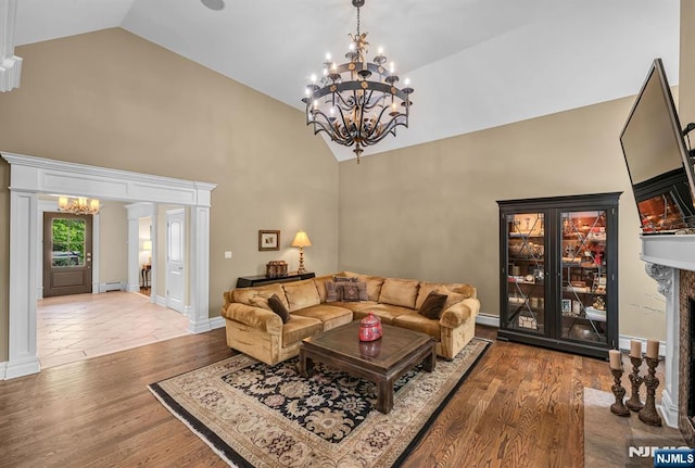 living area featuring an inviting chandelier, a baseboard heating unit, wood finished floors, and high vaulted ceiling