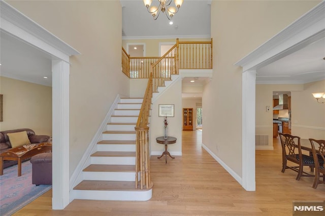 stairs featuring ornamental molding, wood finished floors, and a chandelier