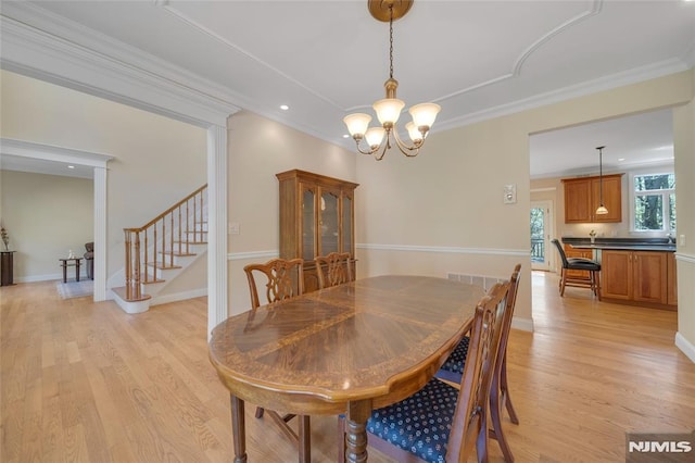 dining space featuring stairway, ornamental molding, light wood finished floors, and a notable chandelier