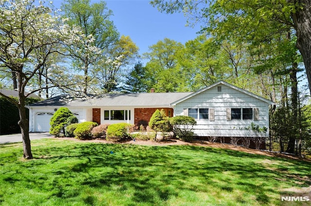 ranch-style house featuring concrete driveway, an attached garage, a chimney, and a front lawn