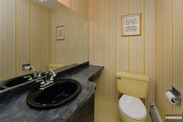 bathroom with toilet, wallpapered walls, a baseboard heating unit, and vanity