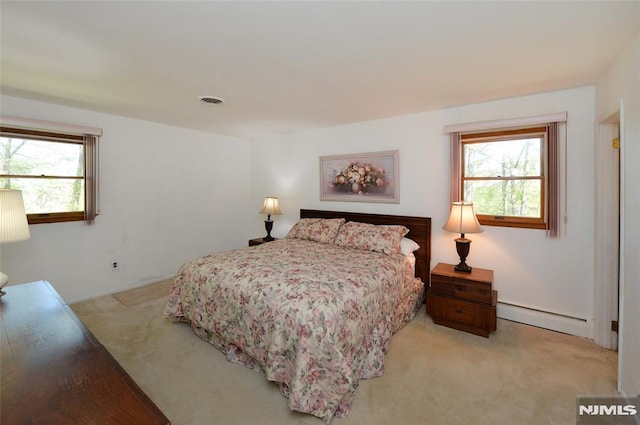 bedroom featuring light colored carpet, a baseboard heating unit, and multiple windows