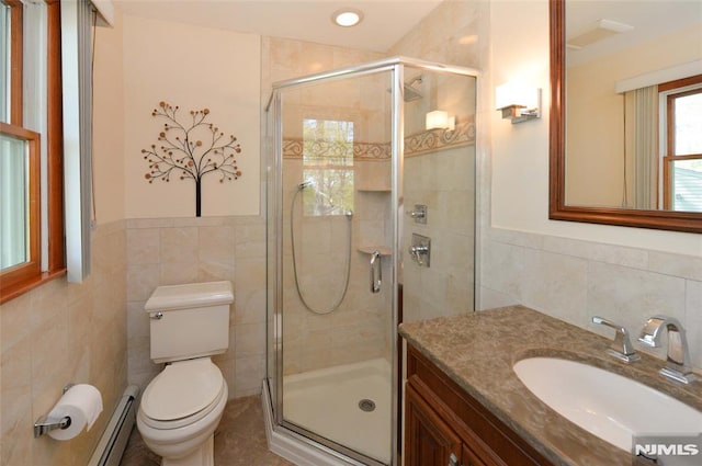 bathroom with vanity, a stall shower, a baseboard heating unit, and tile walls