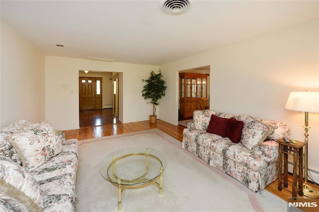 living area featuring visible vents, wood finished floors, and baseboard heating
