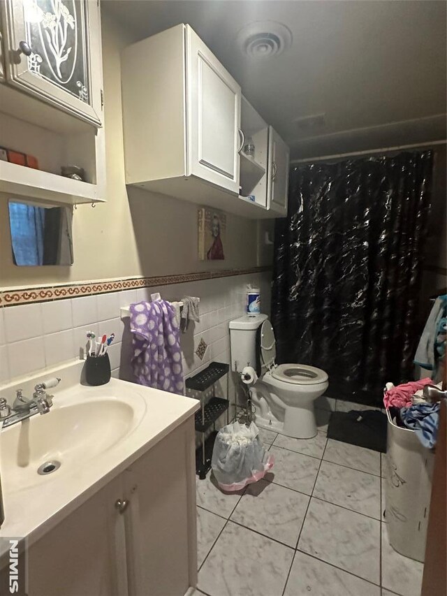 bathroom featuring tile walls, toilet, vanity, tile patterned floors, and curtained shower