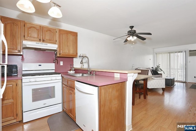 kitchen with a sink, a peninsula, white appliances, under cabinet range hood, and a ceiling fan