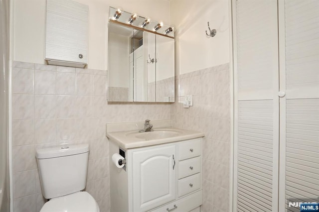 bathroom featuring tile walls, vanity, and toilet