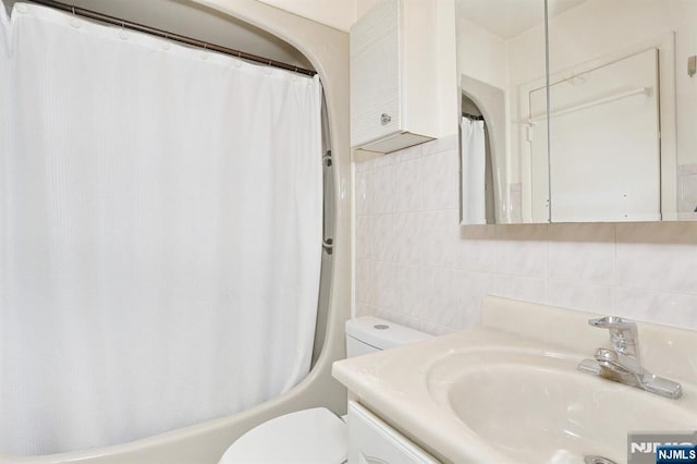 bathroom featuring vanity, toilet, tile walls, tasteful backsplash, and shower / tub combo