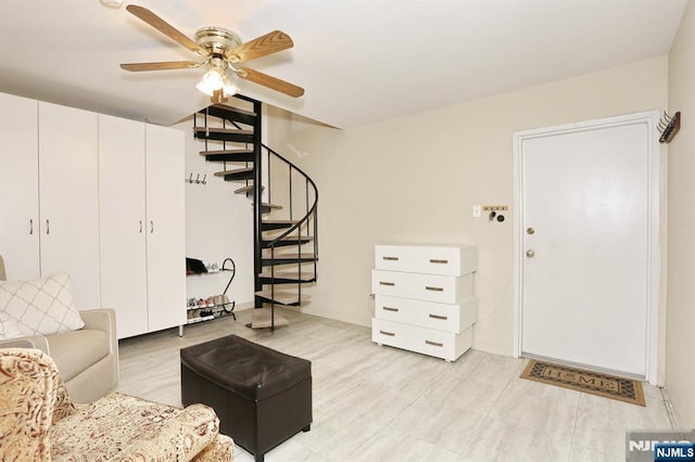 living area with a ceiling fan and stairs
