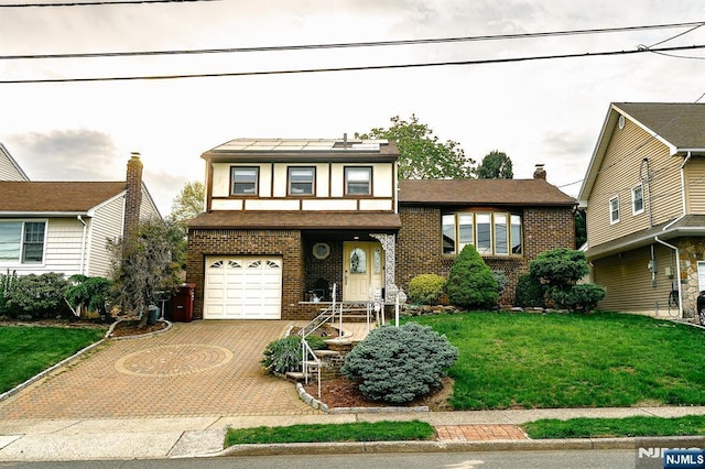 view of front facade featuring brick siding, a garage, a front lawn, and decorative driveway
