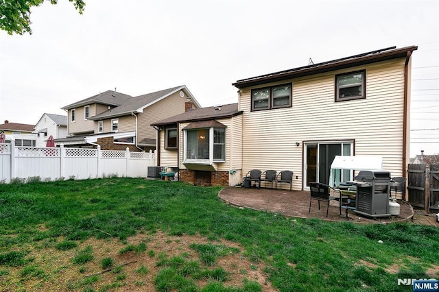 rear view of property with a fenced backyard, a patio area, central AC, and a yard