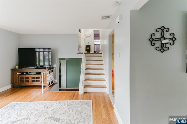 staircase with baseboards, visible vents, and wood finished floors