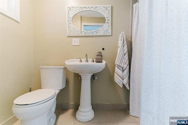 bathroom with toilet, tile patterned floors, and baseboards