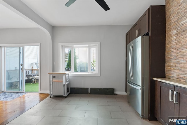 kitchen with dark brown cabinets, light countertops, freestanding refrigerator, a ceiling fan, and baseboards