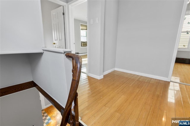 corridor featuring baseboards and hardwood / wood-style floors