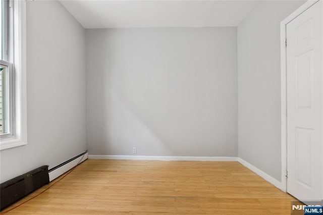 spare room featuring baseboards, a healthy amount of sunlight, and light wood finished floors
