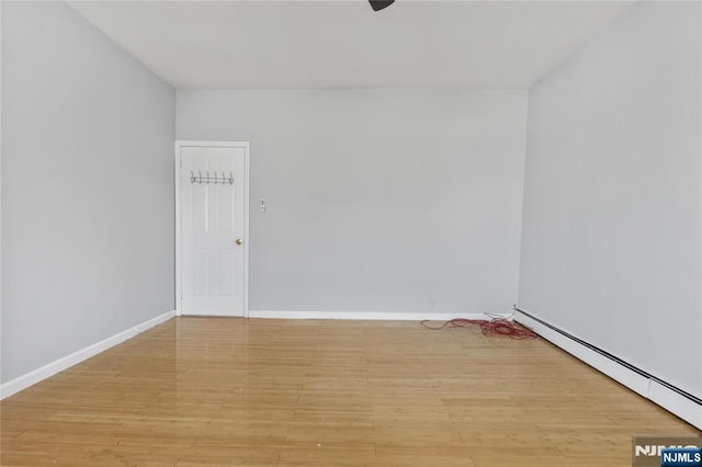 spare room with baseboards, a baseboard heating unit, and light wood-style flooring