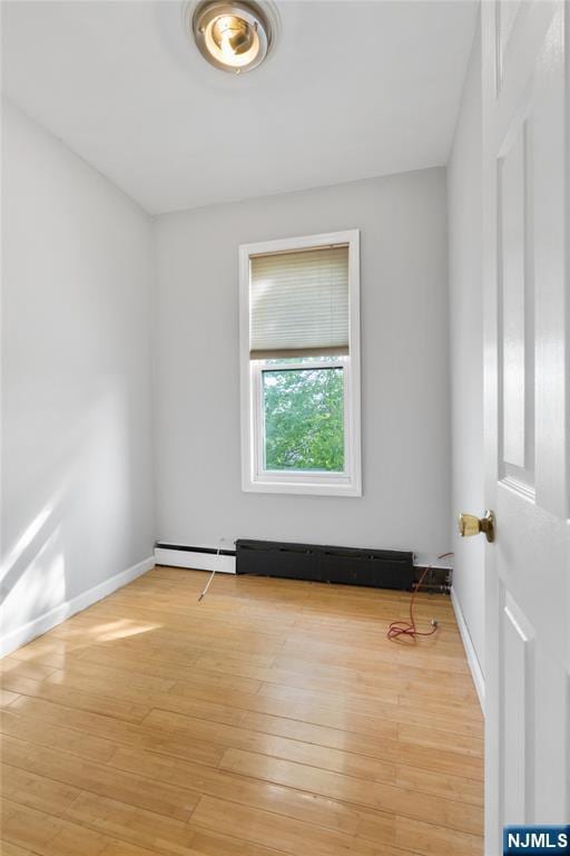 unfurnished room with baseboards, a baseboard radiator, and light wood-style flooring