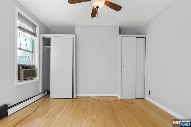 unfurnished bedroom with multiple closets, a baseboard radiator, cooling unit, and wood finished floors