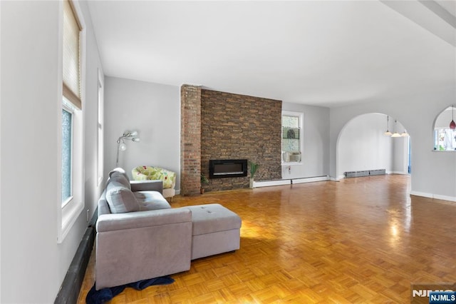 living area with a healthy amount of sunlight, arched walkways, and baseboard heating