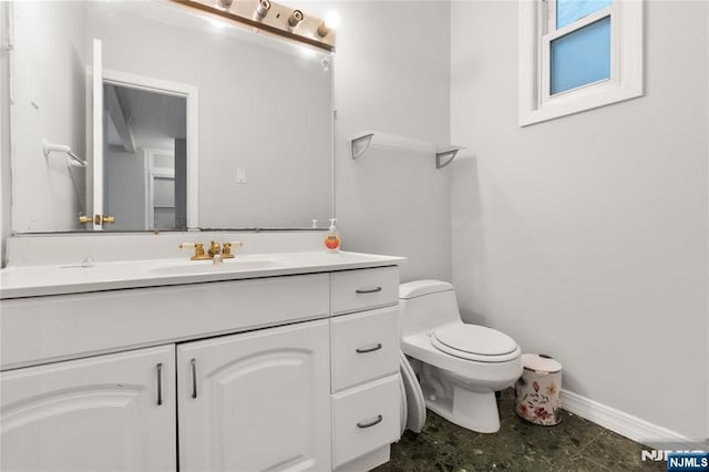 bathroom with baseboards, toilet, and vanity