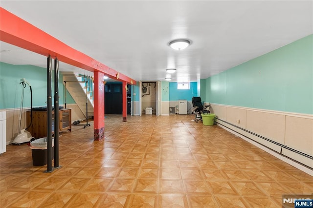 below grade area featuring stairway, wainscoting, and a baseboard heating unit
