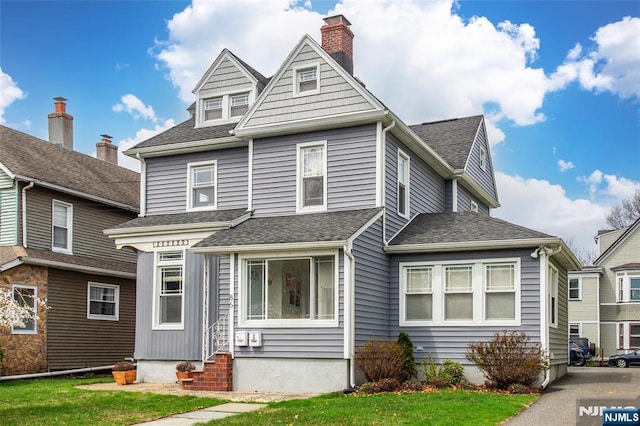 american foursquare style home with roof with shingles, a chimney, entry steps, and a front lawn