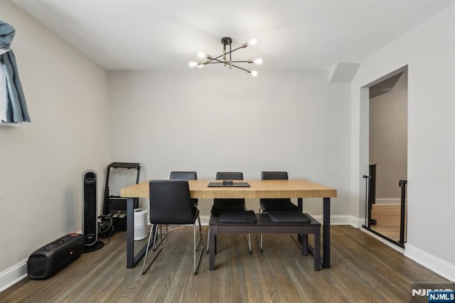 dining space with baseboards, wood finished floors, and a notable chandelier