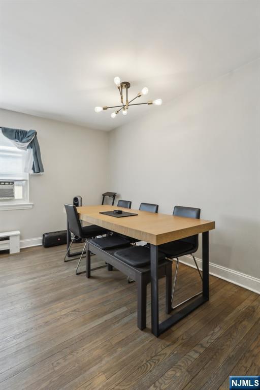 dining room with baseboards, cooling unit, a chandelier, and dark wood-style floors