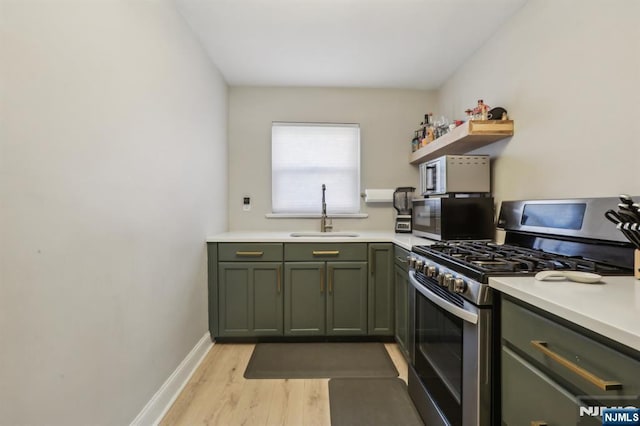 kitchen with black microwave, open shelves, stainless steel gas stove, a sink, and green cabinetry
