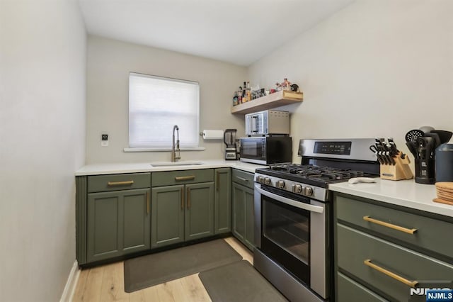 kitchen featuring open shelves, stainless steel gas stove, a sink, light countertops, and green cabinetry