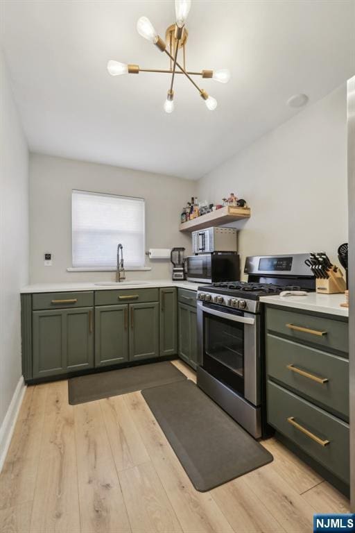 kitchen featuring green cabinetry, a notable chandelier, a sink, stainless steel range with gas stovetop, and light countertops