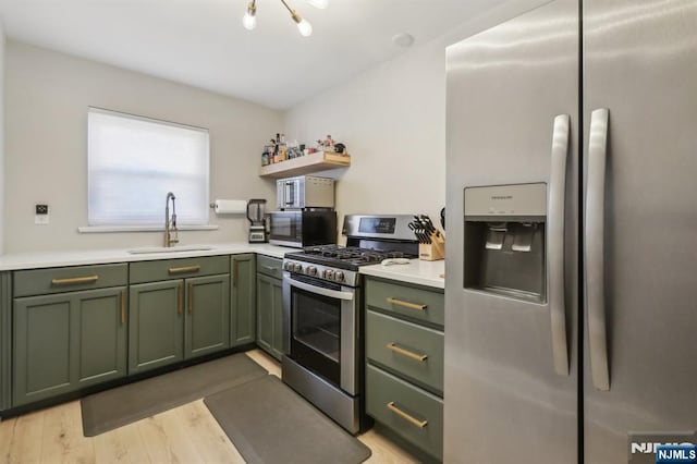 kitchen with a sink, appliances with stainless steel finishes, green cabinets, and light countertops