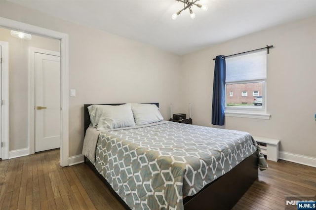 bedroom with baseboards, an inviting chandelier, and hardwood / wood-style floors