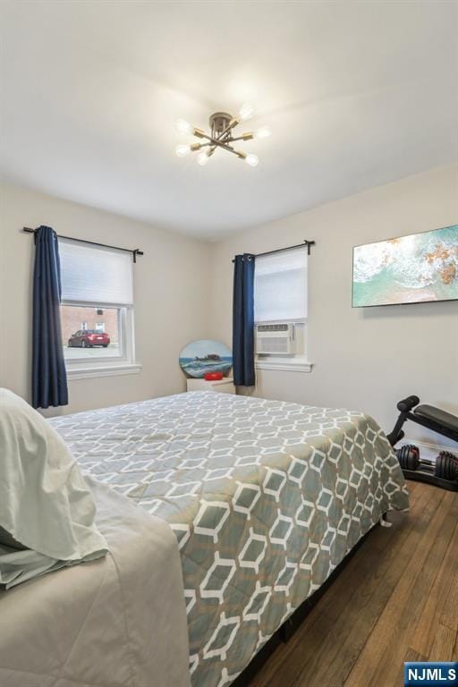 bedroom with wood finished floors, a chandelier, and cooling unit